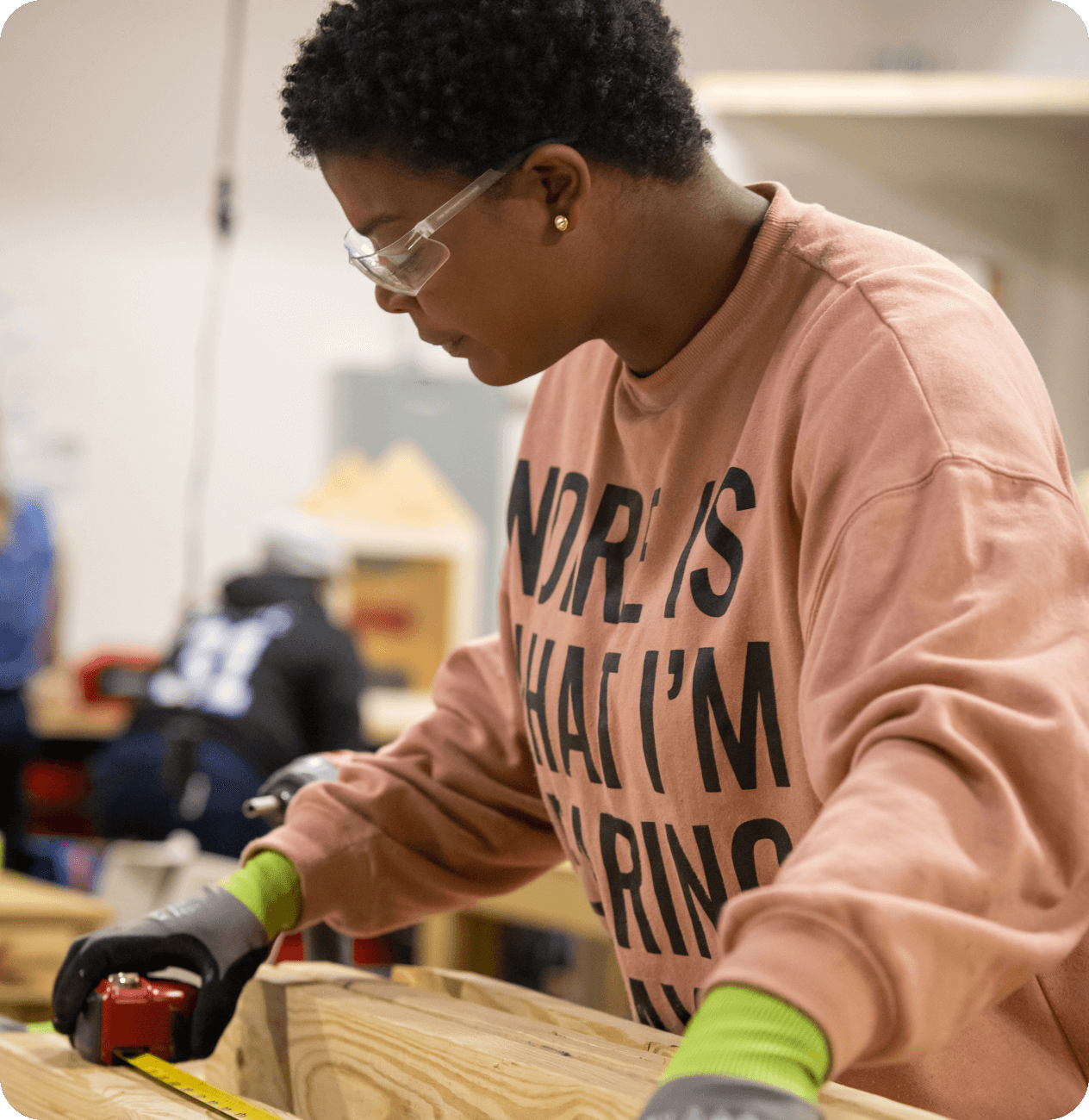 Woman working in the Track to the Trades Program measuring lumber