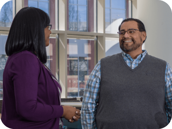 Two Corporate associates having a conversation in an open workspace at Corporate headquarters