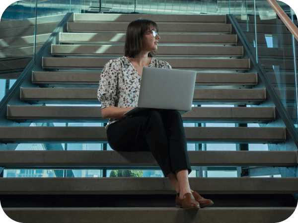 Lowe's associate working on her laptop on the steps of the Tech Hub