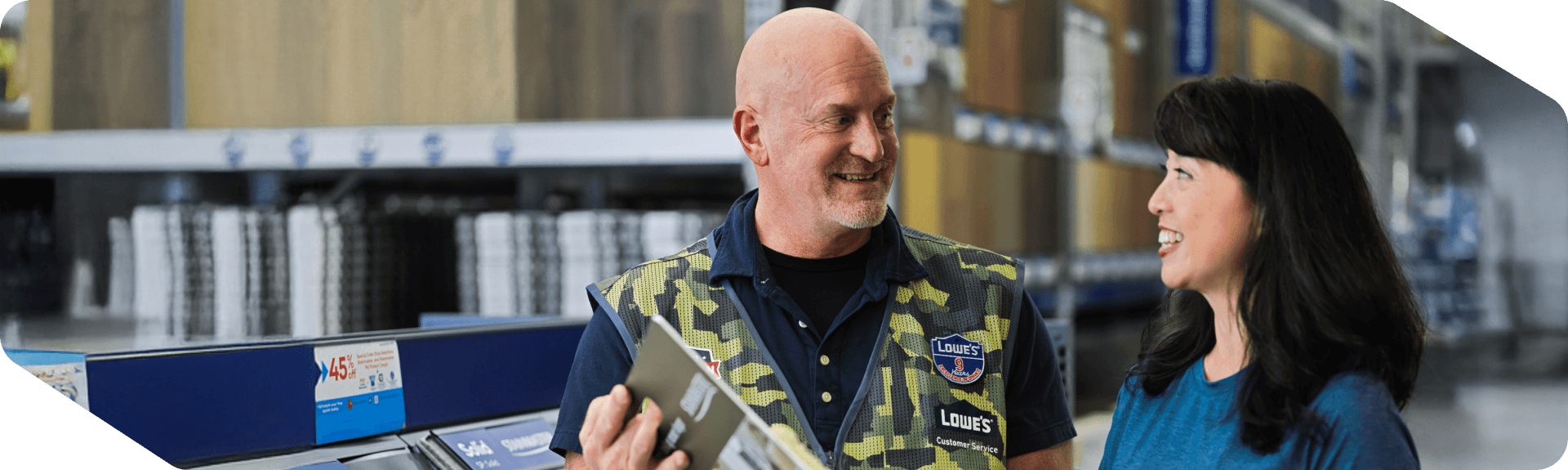 Lowe's store associate wearing a military vest assisting a customer with a carpet purchase