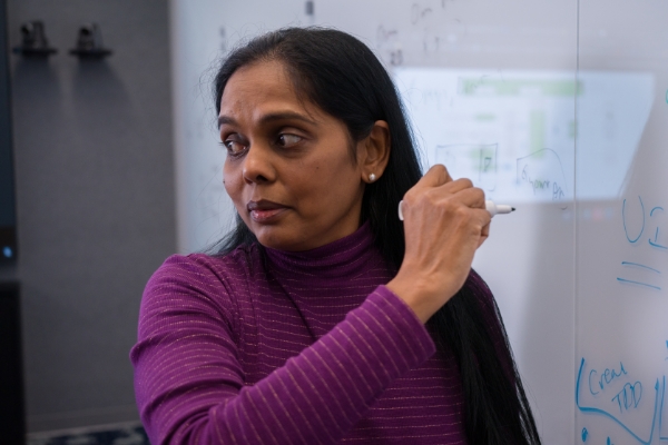 Tech associate writing on a whiteboard during a meeting