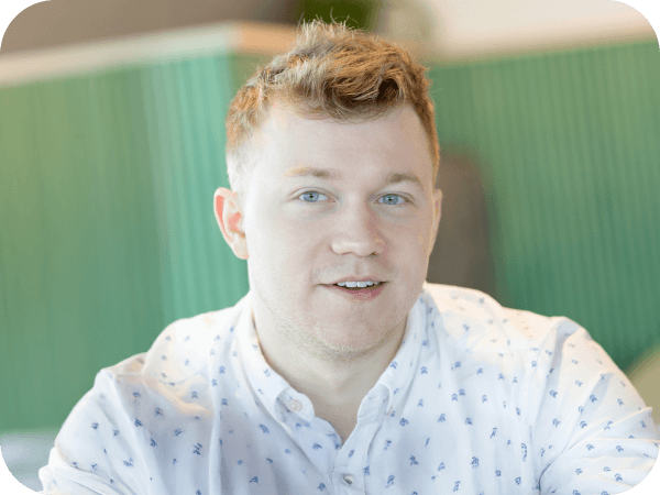 Lowe’s associate smiling in a light-colored shirt, seated indoors.