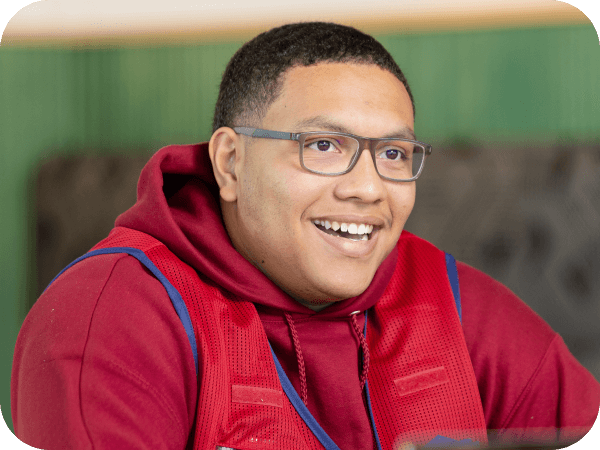 Lowe’s associate in glasses and a red hoodie smiling indoors.