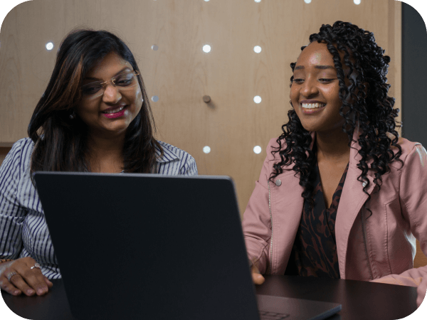 Two Lowe’s team members smiling while working together at a laptop.