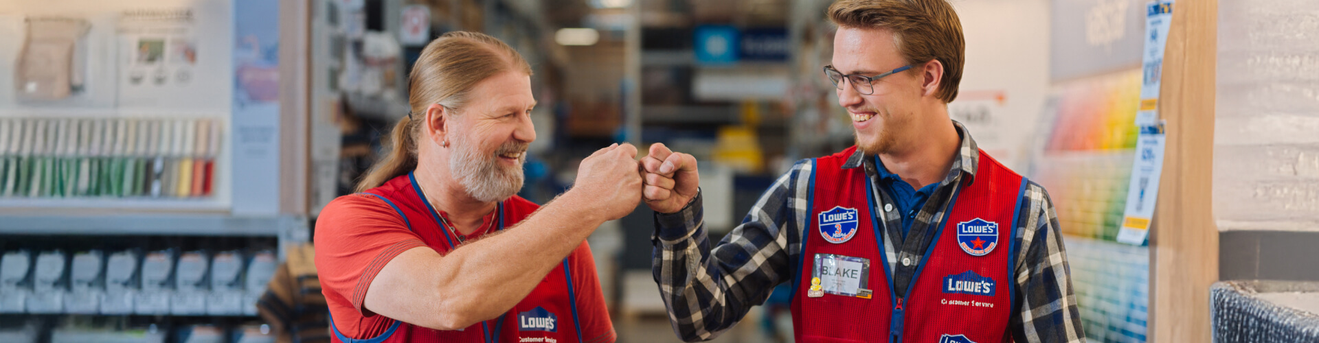 Two Lowe's associates fist bumping in the paint department