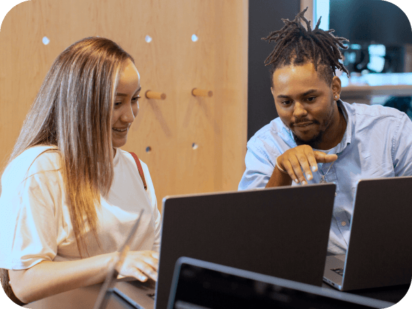 Two associates working on laptops in a conference room