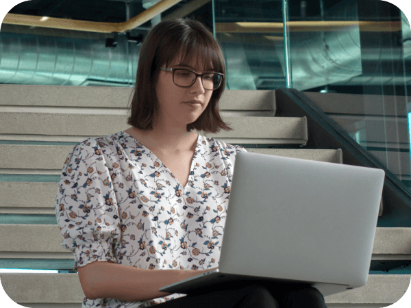 Lowe's Tech associate working on her laptop on the steps of the Tech Hub