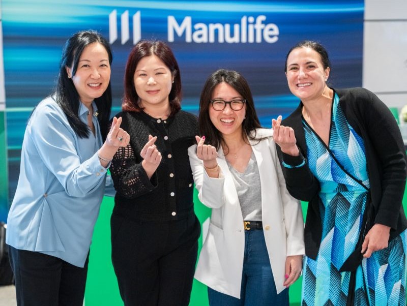Four Manulife colleagues standing together in front of a Manulife-branded display.
