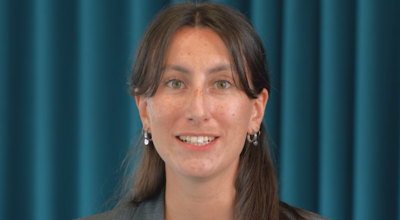 Close-up portrait of Alice, a Consultant at Orange Business, smiling against a professional teal-colored curtain background.