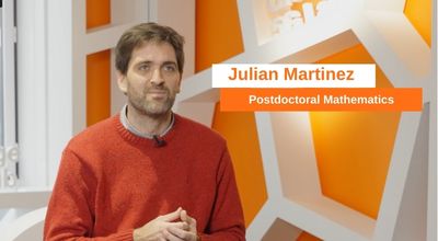 Julian, a Mathematics Postdoctoral fellow, posing for a professional headshot in a bright, contemporary workspace.