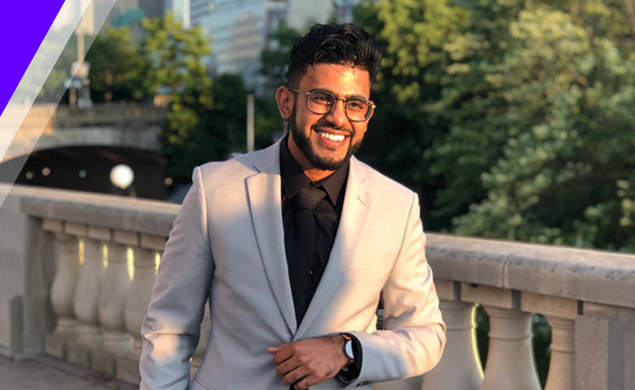 Sajid outside smiling adjusting suit