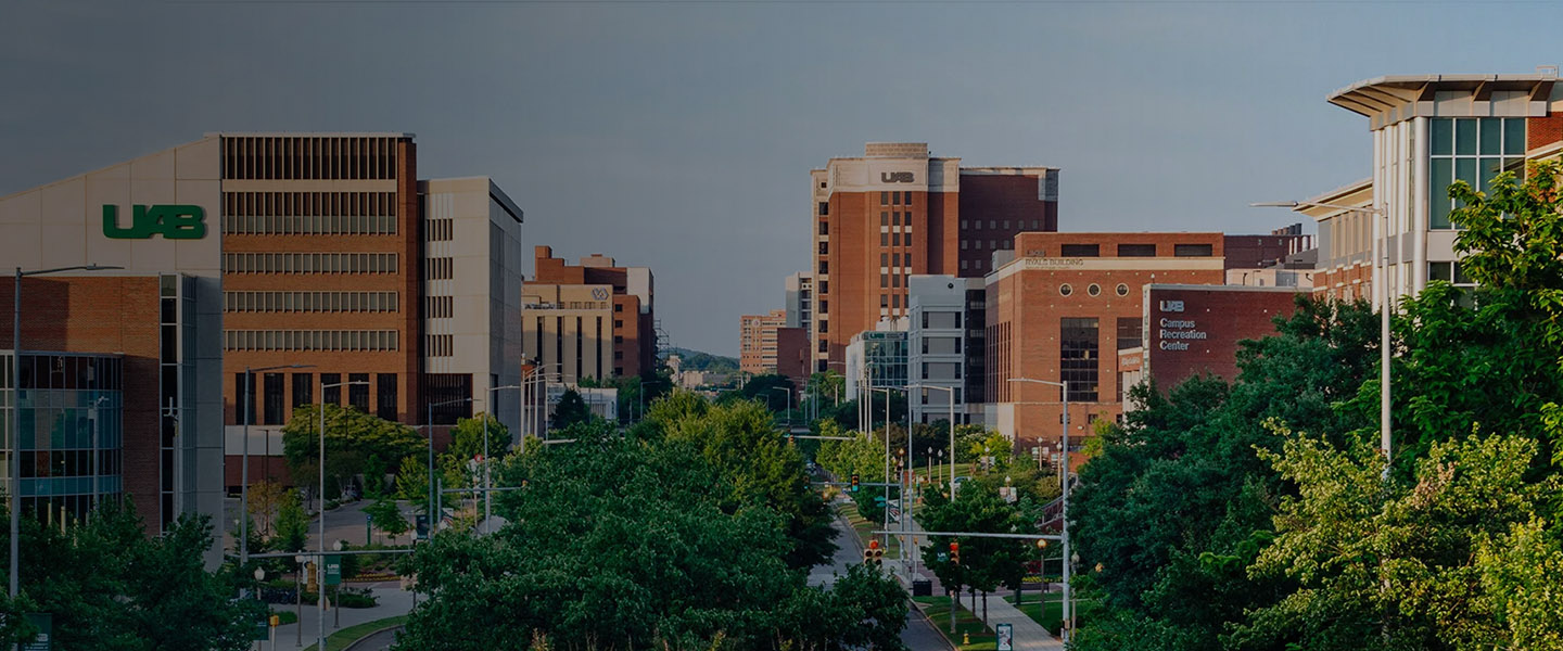A view of the University of Alabama at Birmingham (UAB) campus with several modern academic buildings, trees, and a main road running through the center.