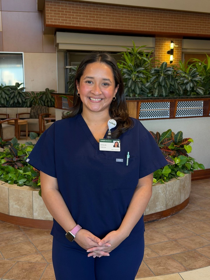 White female in navy blue scrubs standing and smiling